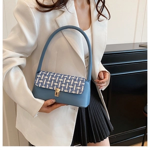Detail of light blue leather and tweed underarm bag with gold twist lock on model