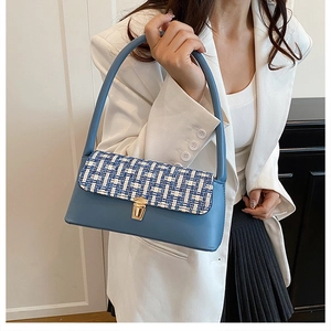 Detail of tweed flap and golden buckle on blue leather shoulder bag with a model