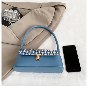 Detail of blue leather and tweed patchwork underarm bag with gold metal buckle