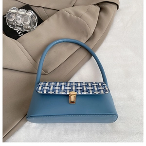 Detail of tweed flap texture and golden buckle on the minimalist blue handbag