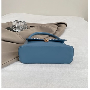 Detail view showing smooth leather stitching and bottom structure of the blue handbag