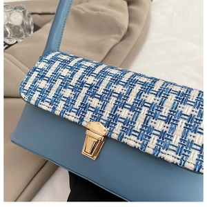 Detail of blue leather and woven fabric handbag with a golden rectangular metal clasp