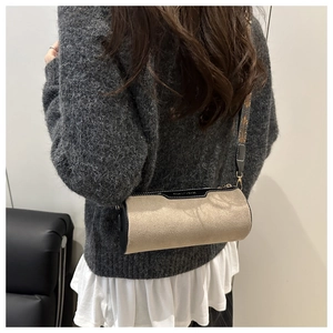 Detail of beige suede cylinder bag with vintage jacquard strap and gold hardware