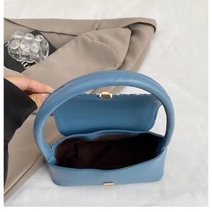 Detail view of the blue handbag's interior with golden metal lock and brown lining