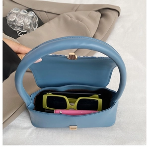 Detailed view of blue leather handbag interior with sunglasses and lipstick inside
