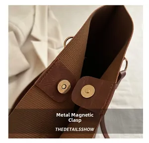 Detail of golden magnetic closure on brown striped fabric tote bag with leather trim