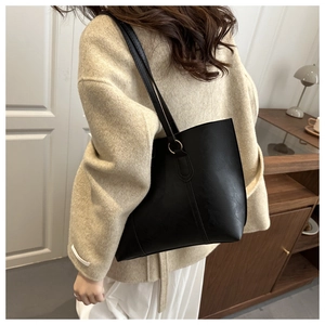 Detail view of a minimalist black leather tote bag featuring sleek long shoulder straps