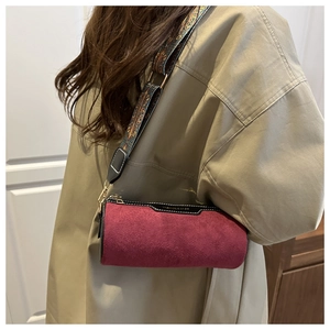 Detail of burgundy suede cylindrical crossbody bag with vintage ethnic patterned wide strap