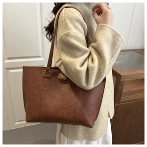 Close-up of vintage brown leather tote bag showing fine stitching and fashion tag detail