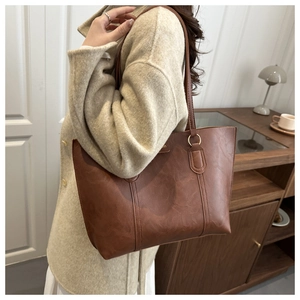 Detail of caramel leather tote bag showing smooth texture and metallic ring on the shoulder