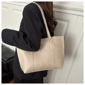Detailed close-up of a beige large tote bag with vintage texture and sleek shoulder straps