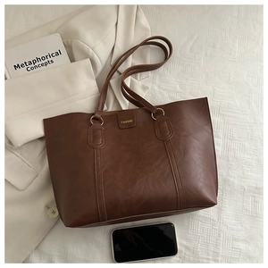 Detailed view of dark brown tote bag with retro leather texture and gold logo