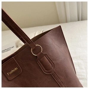 Close-up of brown textured leather tote bag with gold ring hardware and embossed detail
