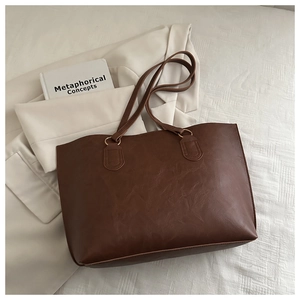 Close-up of brown faux leather tote bag texture with gold ring strap attachment