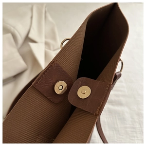 Macro detail of brown tote bag with striped fabric lining and gold magnetic closure