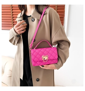 Close-up of bright pink quilted handbag featuring a gold heart-shaped rotary lock detail