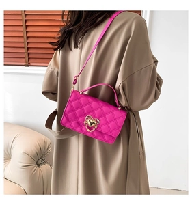 Close-up of rose red quilted crossbody bag with golden heart hardware and chain details