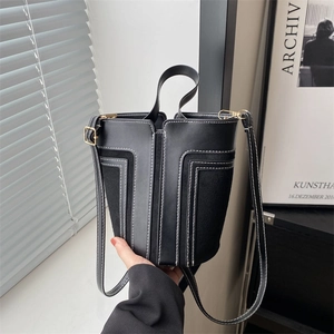 Fashionable black contrast stitch bucket bag with gold hardware and top handle strap
