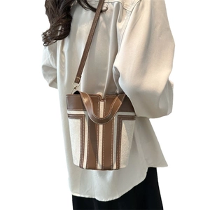Minimalist canvas and leather bucket bag with brown vertical stripes and adjustable strap