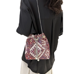 Ethnic woven bucket bag with geometric patterns and silver chain strap worn by model