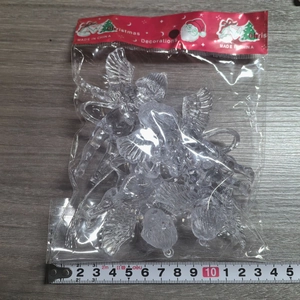 Close-up of four transparent acrylic angel Christmas tree ornaments with a measuring tape