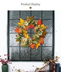 Detailed close-up of autumn harvest wreath with pumpkins and maple leaves on a black frame