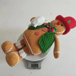 Gingerbread man plush toy with knitted texture being weighed on a digital scale
