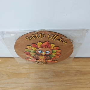Detail of wooden Thanksgiving turkey sign with Gobble till you wobble text in packaging