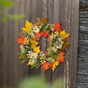Macro detail of autumn wreath featuring white pumpkins, maple leaves, and berries on wood