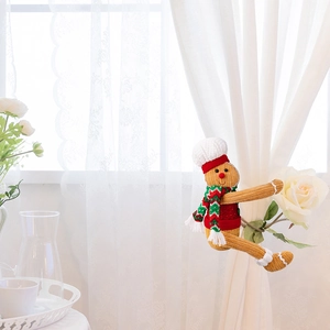 Macro shot of knitted gingerbread man curtain tieback with chef hat and striped scarf
