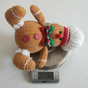Close-up showing a 50.3g gingerbread man plush doll with a Christmas hat on a scale