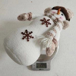 Dettaglio di un pupazzo di neve di peluche natalizio pesato su una bilancia digitale