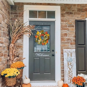 Macro detail of autumn wreath with white pumpkins and maple leaves on a front door