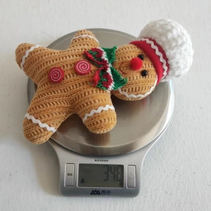Detailed view of gingerbread man plush pendant on a scale weighing 34.8 grams