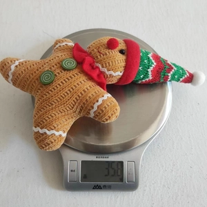 Macro shot of gingerbread plush pendant showing 35.8g weight on a digital scale