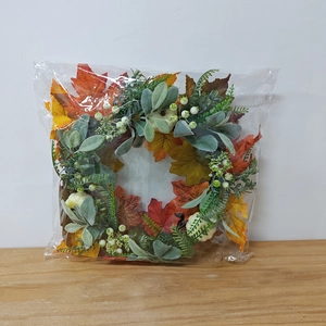 Detail of fall wreath with white pumpkins and maple leaves in protective packaging