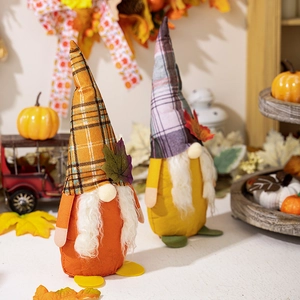 Detail of fall harvest gnomes with maple leaf decor and plaid hats on wooden tray