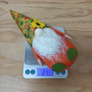 Close-up of fall gnome plush toy with sunflower hat being weighed on a scale