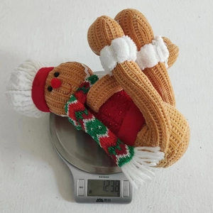 Detail view of a knitted gingerbread man plush figure on a kitchen scale weighing 123.8g