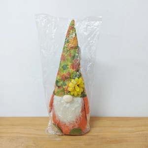 Detail of harvest gnome doll with floral hat and sunflower in plastic packaging