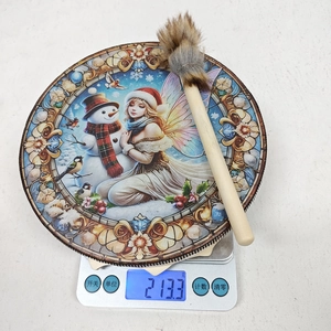 Vue détaillée d'un tambour de Noël avec bonhomme de neige pesant 213,3g sur une balance