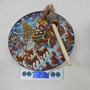 Tambour de Noël avec motif Père Noël pesant 213g sur une balance électronique