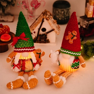 Close-up of glowing Christmas gingerbread gnomes with knitted hats and warm LED lights