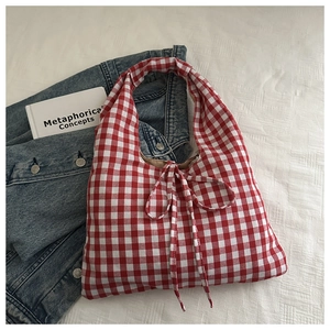 Detail of red and white plaid fabric handbag with bow knot and texture on white background