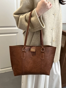 Brown litchi grain leather tote bag with gold hardware shown on a female model