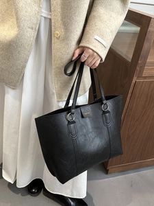 Minimalist black PU leather tote bag with gold metal rings and top handles on a model