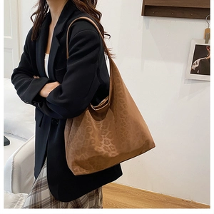 Detail view of the brown leopard print tote bag styled with a professional black blazer