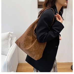 Close-up of a large leopard print tote bag styled with a professional black blazer