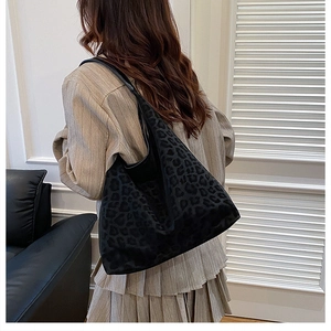 Detail of large leopard print tote bag with black leather shoulder strap on model