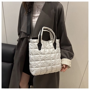 Model wearing a white quilted puffer bucket bag with adjustable black shoulder strap